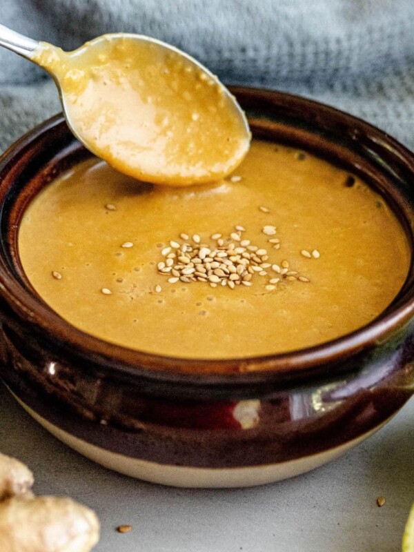 A bowl of soup with a slice of ginger, topped with miso dressing.