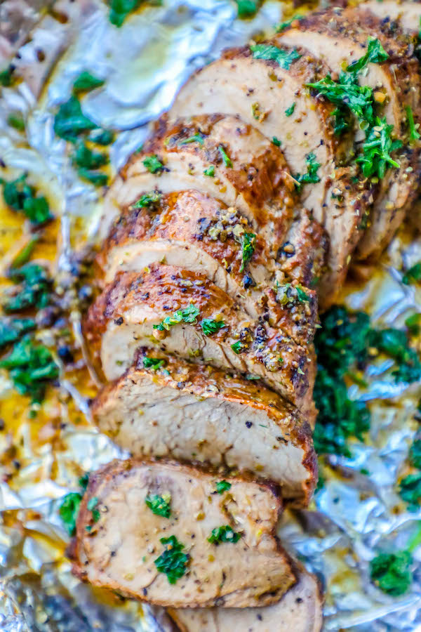 pork tenderloin sliced and garnished with parsley on tinfoil. 