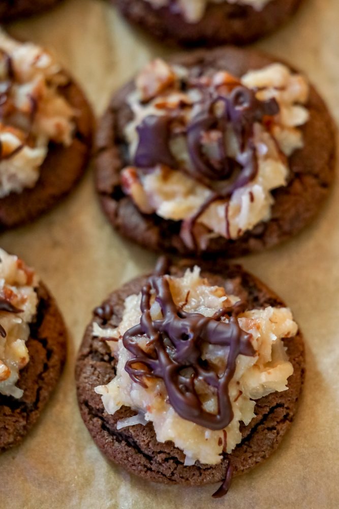 chocolate cookies covered in coconut and nut mixture and a drizzle of chocolate