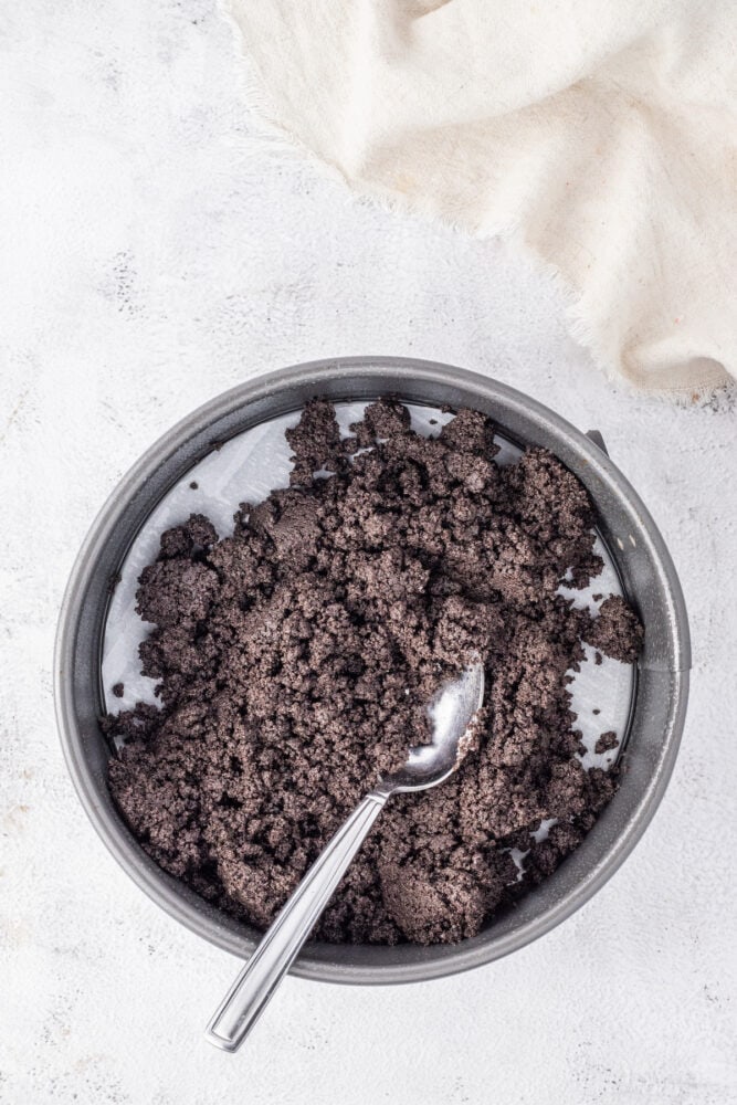 A bowl of chocolate granola with a spoon on a white background.