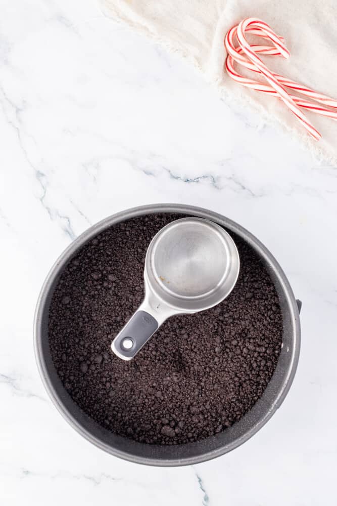 A bowl of cocoa powder with a spoon and candy canes.