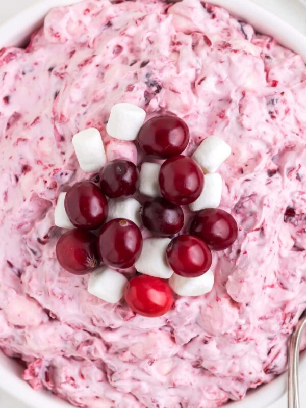 cranberry fluff in a bowl with cranberries and marshmallows on top
