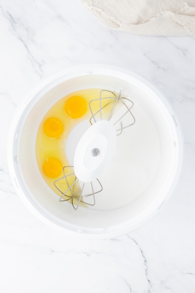 Eggs in a white bowl on a marble countertop.