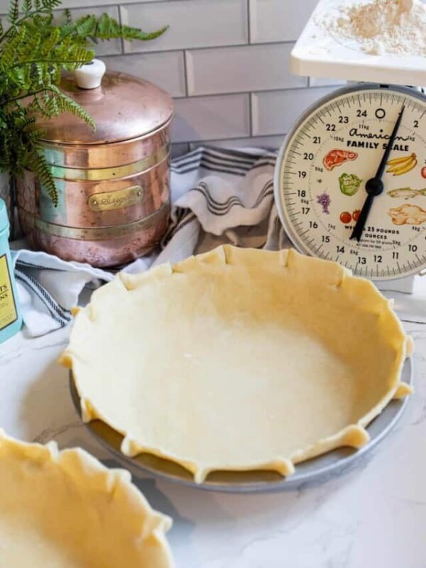 Two pie crusts on a counter next to a scale.