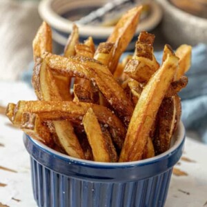 French fries in a blue bowl on a wooden table.