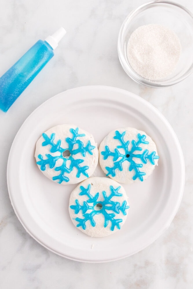 picture of christmas cookies decorated like white wreaths with a blue icing snowflake