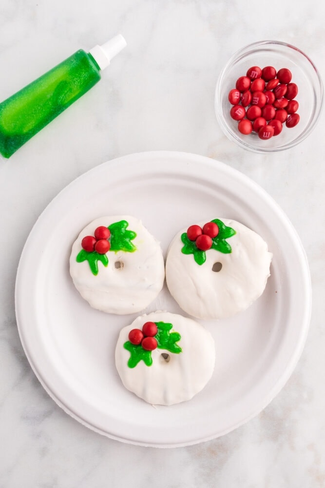 picture of cookies decorated like white christmas wreaths with holly