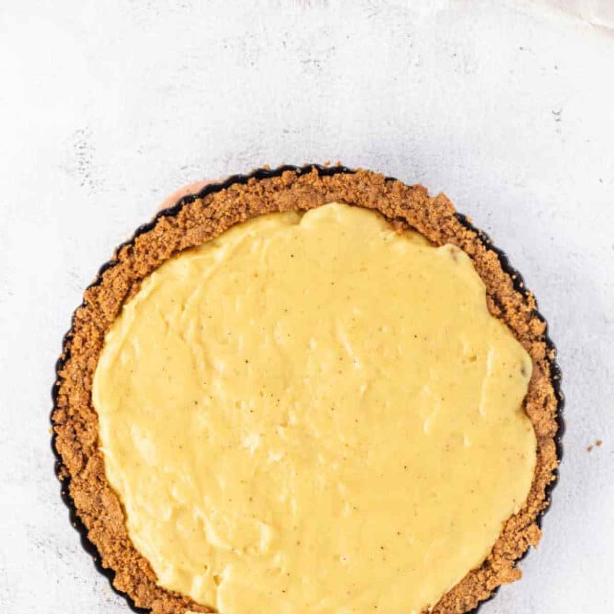A yellow Eggnog Tart on a white surface.