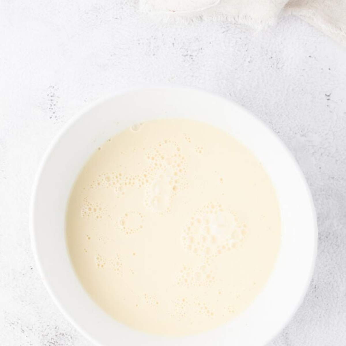 A white bowl with a white liquid in it, resembling eggnog.