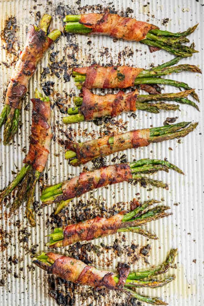 Bacon wrapped asparagus with a garlic twist on a baking sheet.