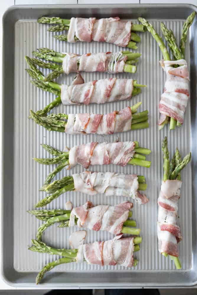 Bacon-wrapped asparagus on a baking sheet.