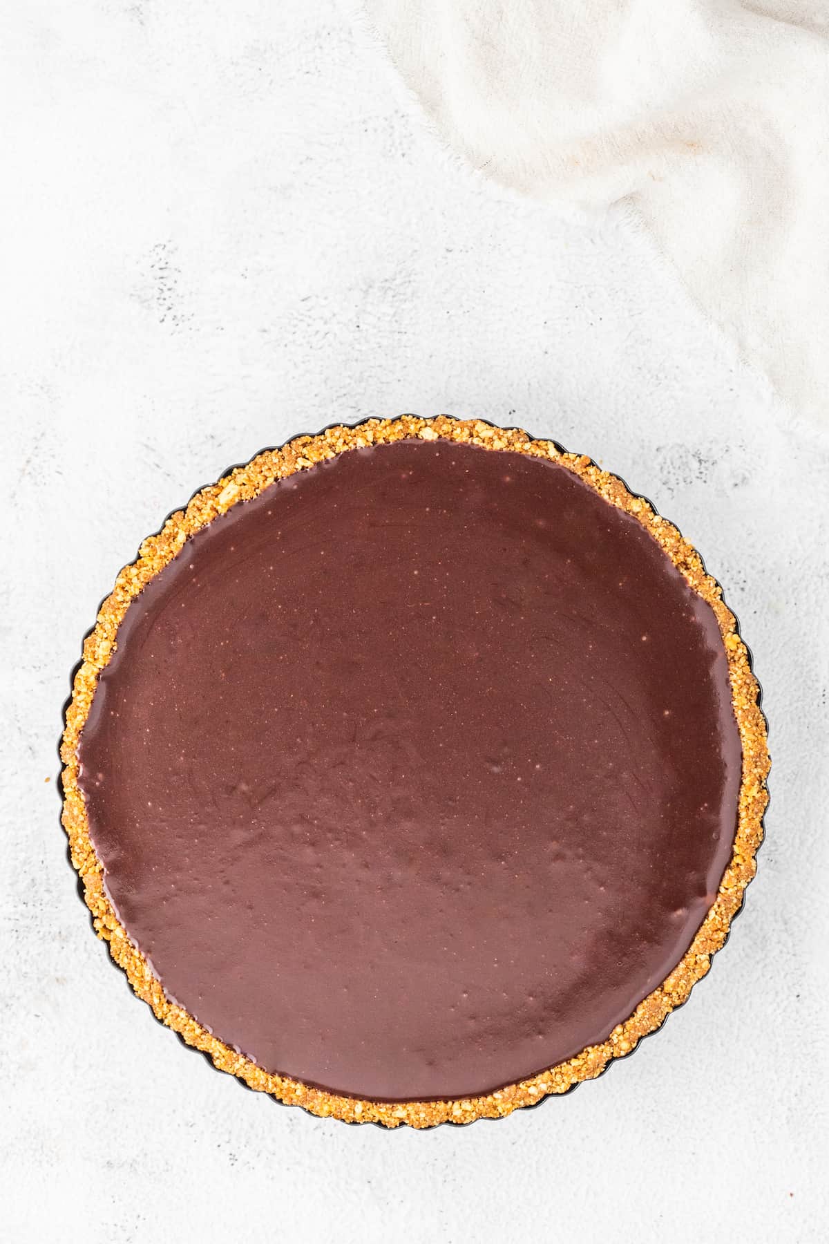 A gingerbread chocolate tart on a white surface.