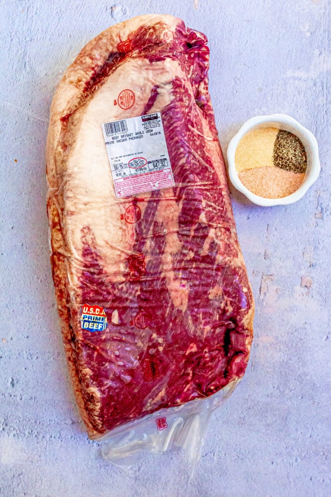 a raw packaged brisket on a table next to spices