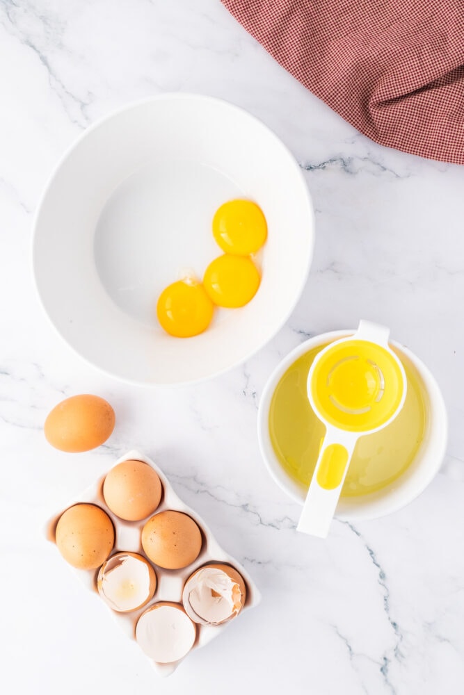 egg yolks and sugar being added to a bowl 