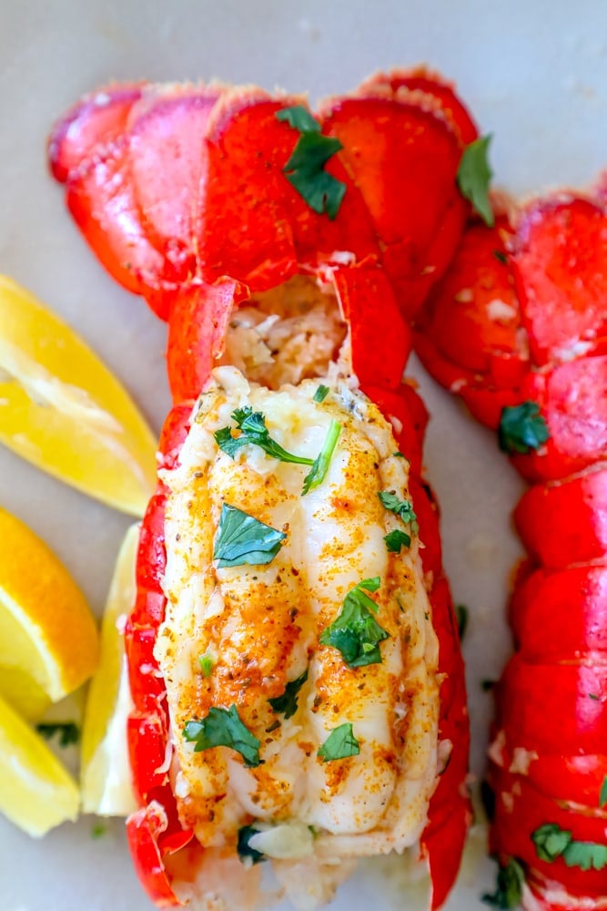 A plate with pressure cooker lobster tails and lemon wedges.