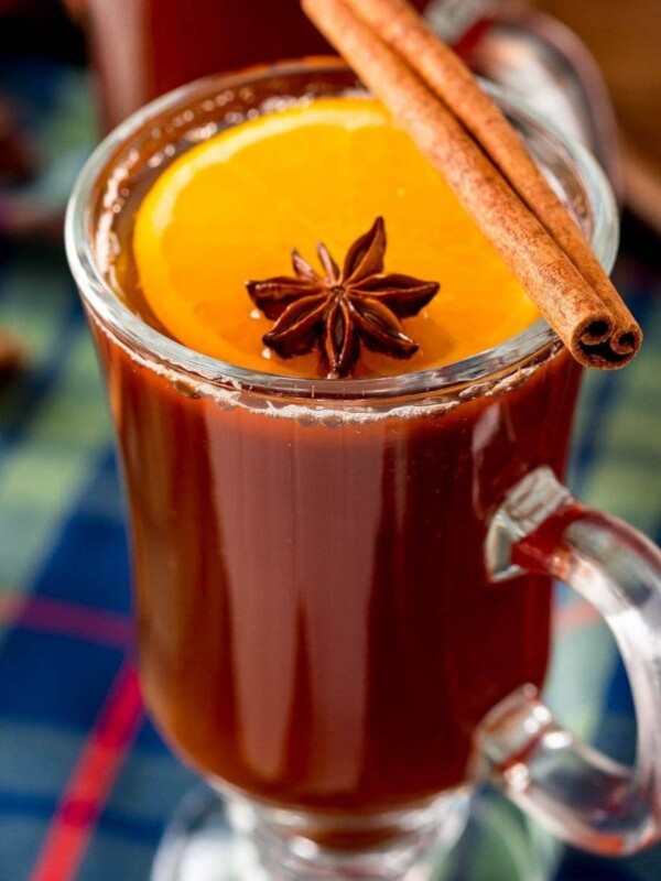 picture of a glass mug with mulled beer, an orange slice, star of anise, and cinnamon stick in it
