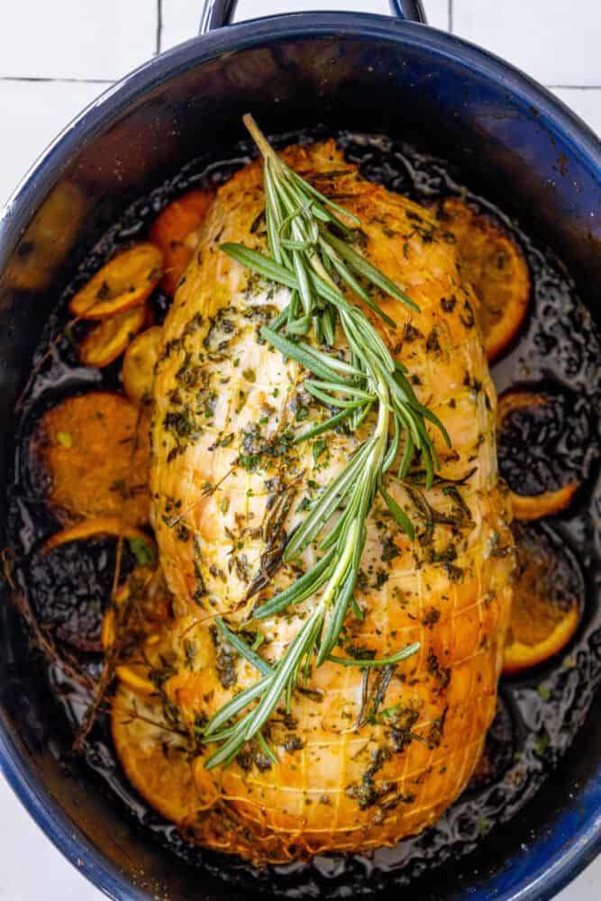 A roast turkey with rosemary sprigs in a blue pot, perfect for an Easy Turkey Dinner for Two.