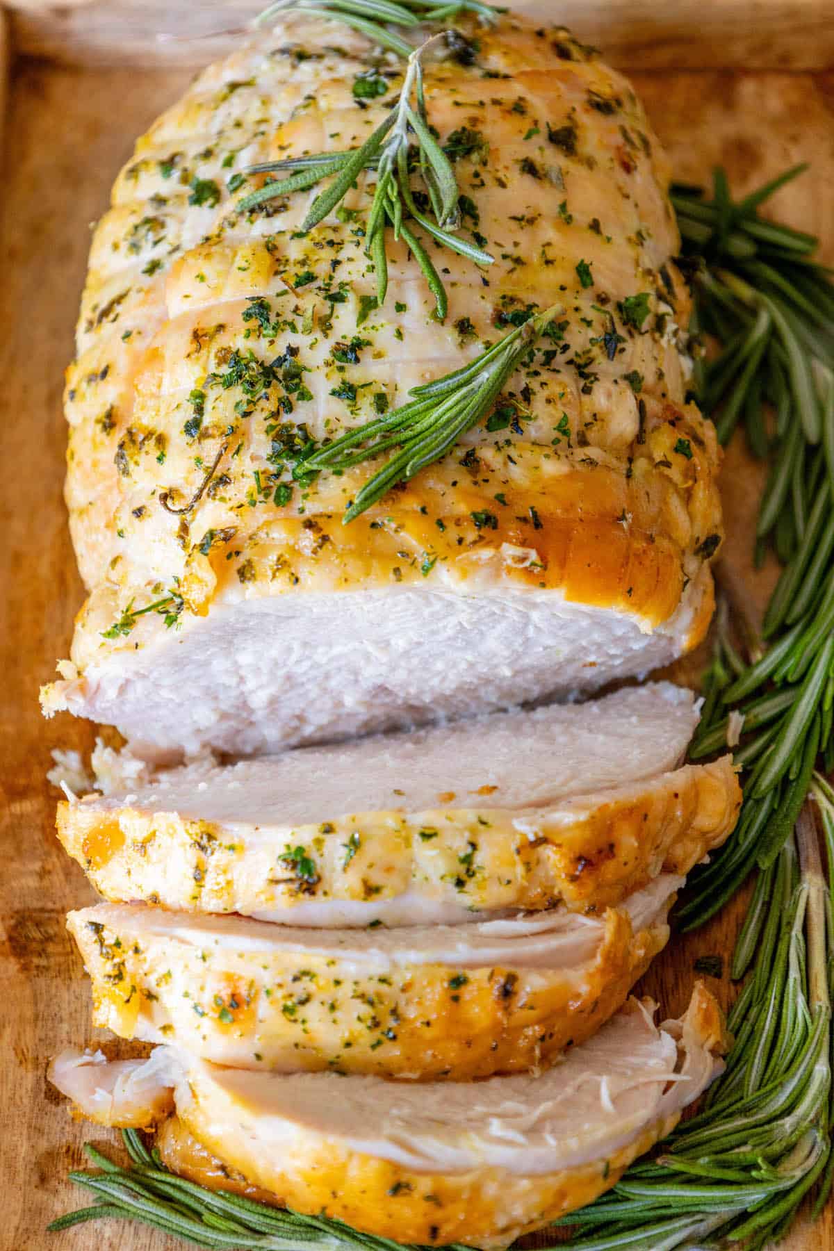 The Best Easy Roasted Turkey Breast Recipe, featuring a sliced roast turkey with rosemary sprigs on a cutting board.