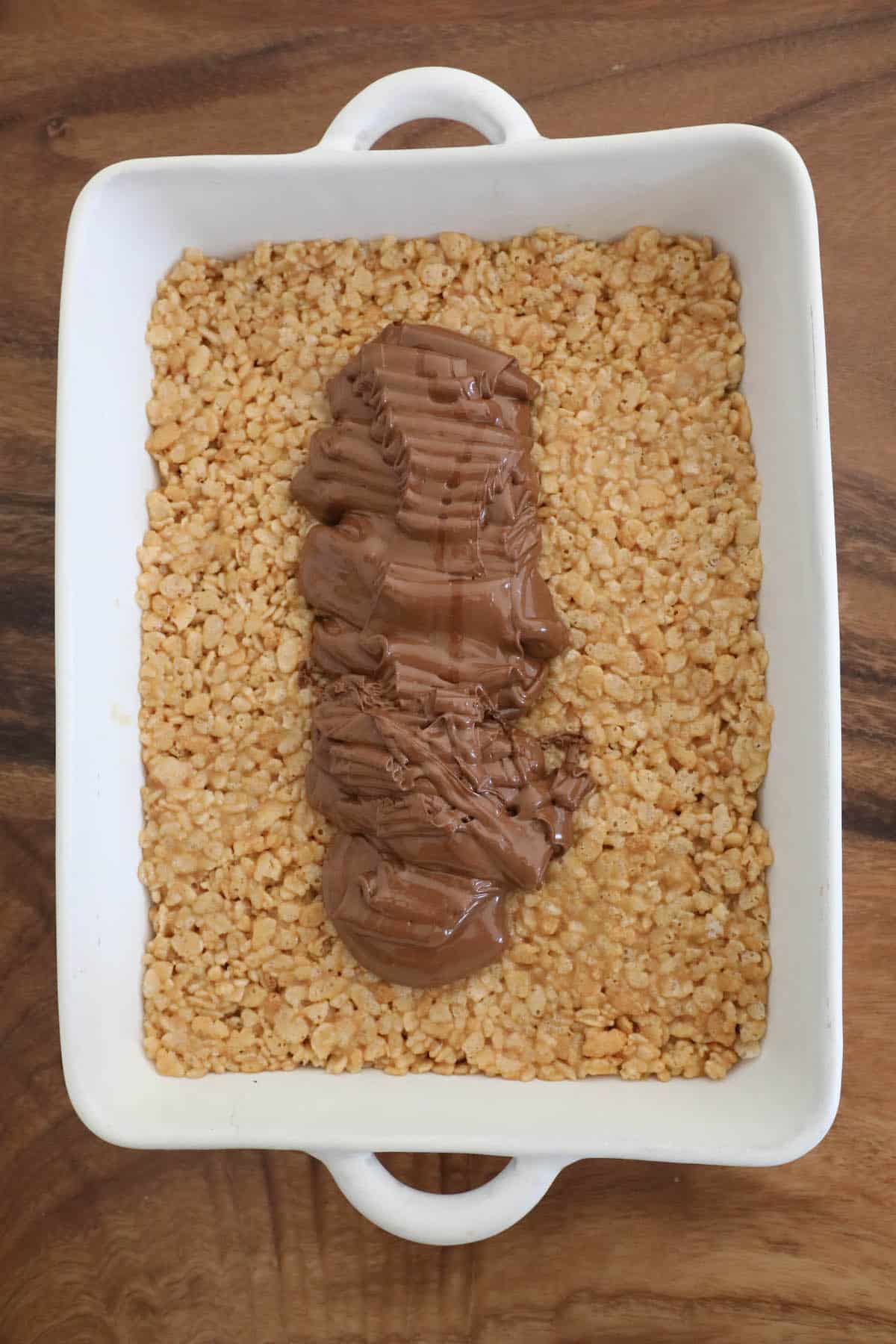 A square dish with scotcheroos and chocolate on top of it.