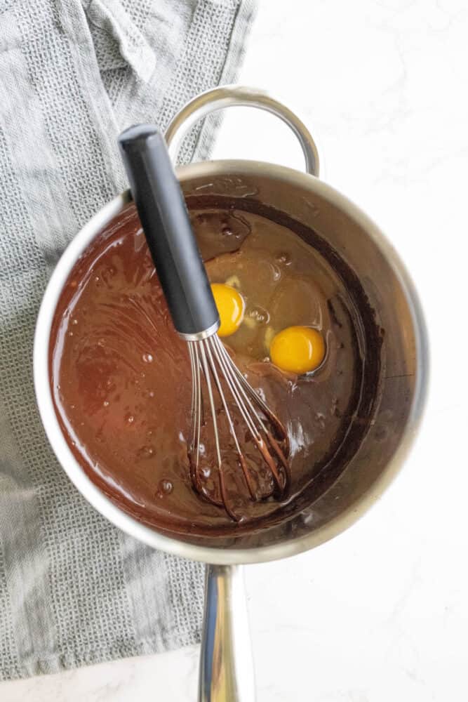 Silky chocolate eggs in a pan with a whisk.