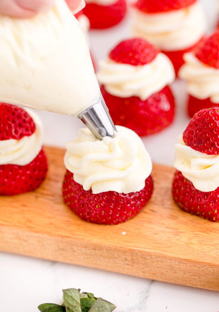 whipped cream being piped onto strawberry