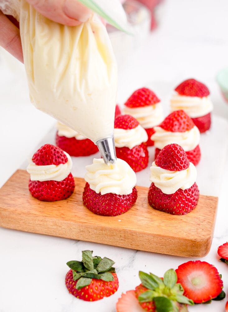whipped cream being piped onto strawberry