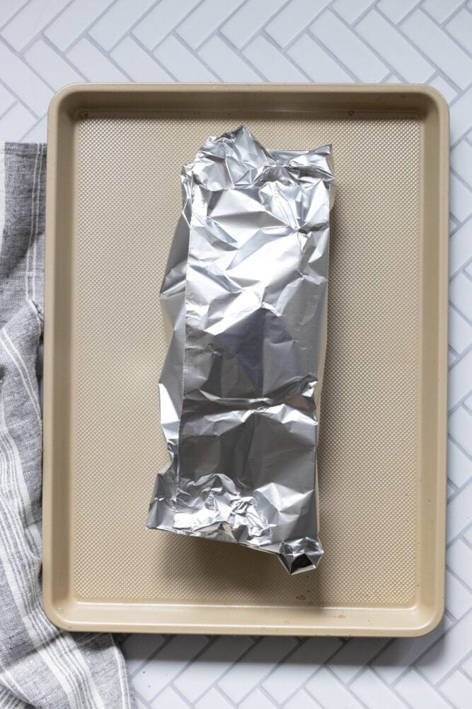 pork tenderloin wrapped in foil on a baking sheet