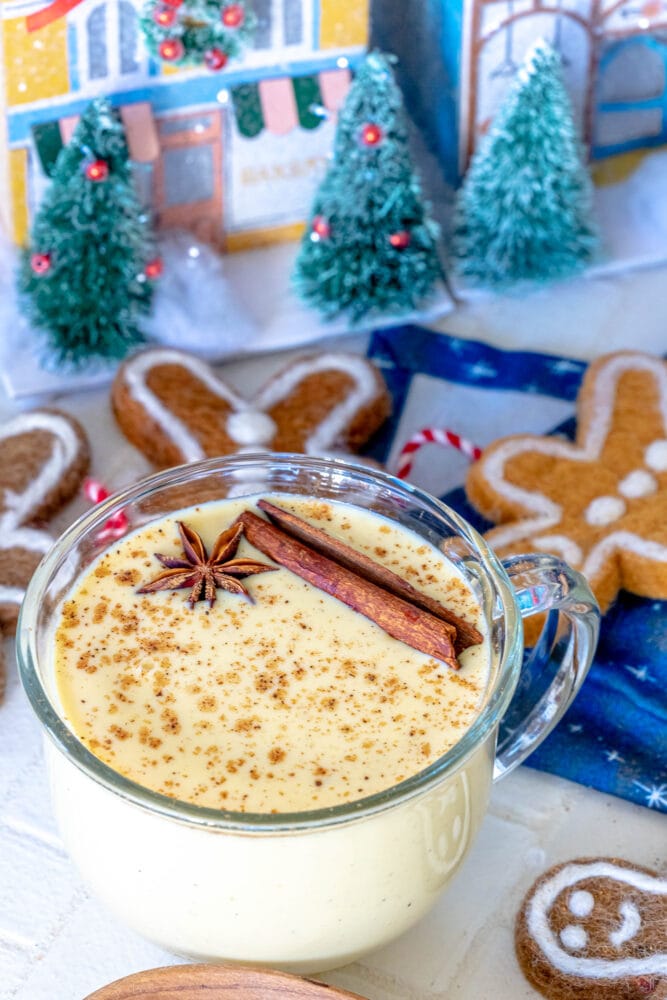 a glass mug with eggnog in it and a stick of cinnamon and star of anise on top