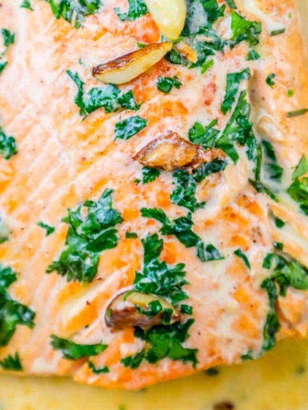 whiskey cream sauce salmon topped with chopped parsley and garlic cloves on top