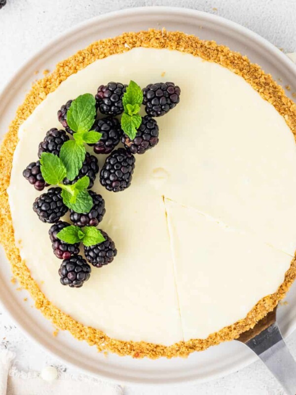 A slice of white chocolate blackberry tart with mint on a white plate.